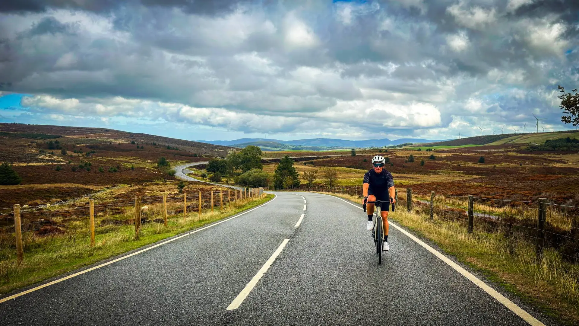 Cyclist on a winding road through the hills of Wales
