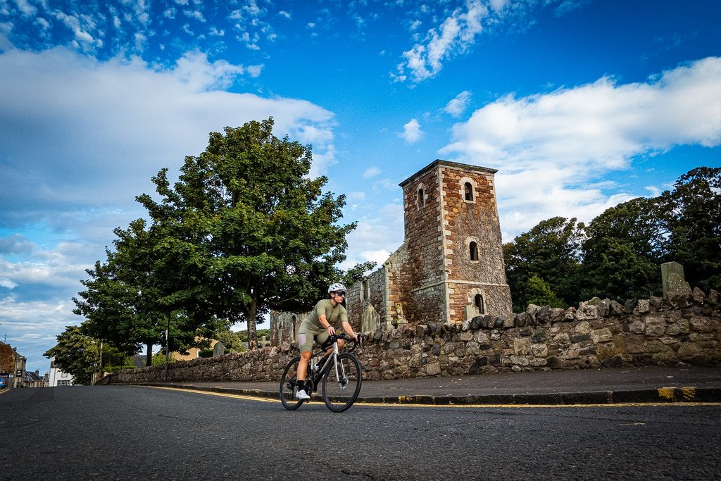 Fietser rijdt langs de oude stenen kerktoren van North Berwick