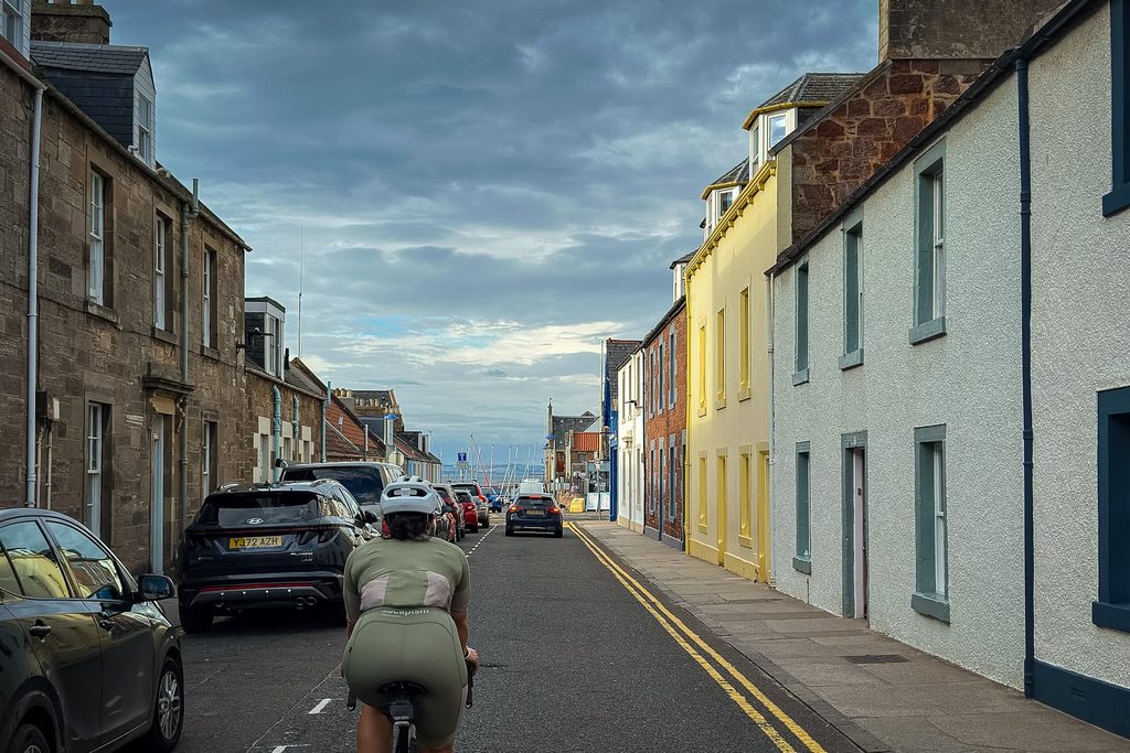 Fietser rijdt door een straat met witte en gele huizen in North Berwick, op weg naar de zee