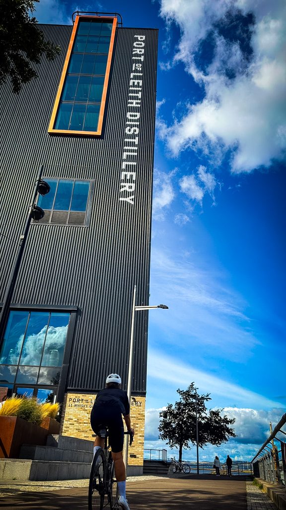 Fietser voor het hoge gebouw van de Port of Leith Distillery