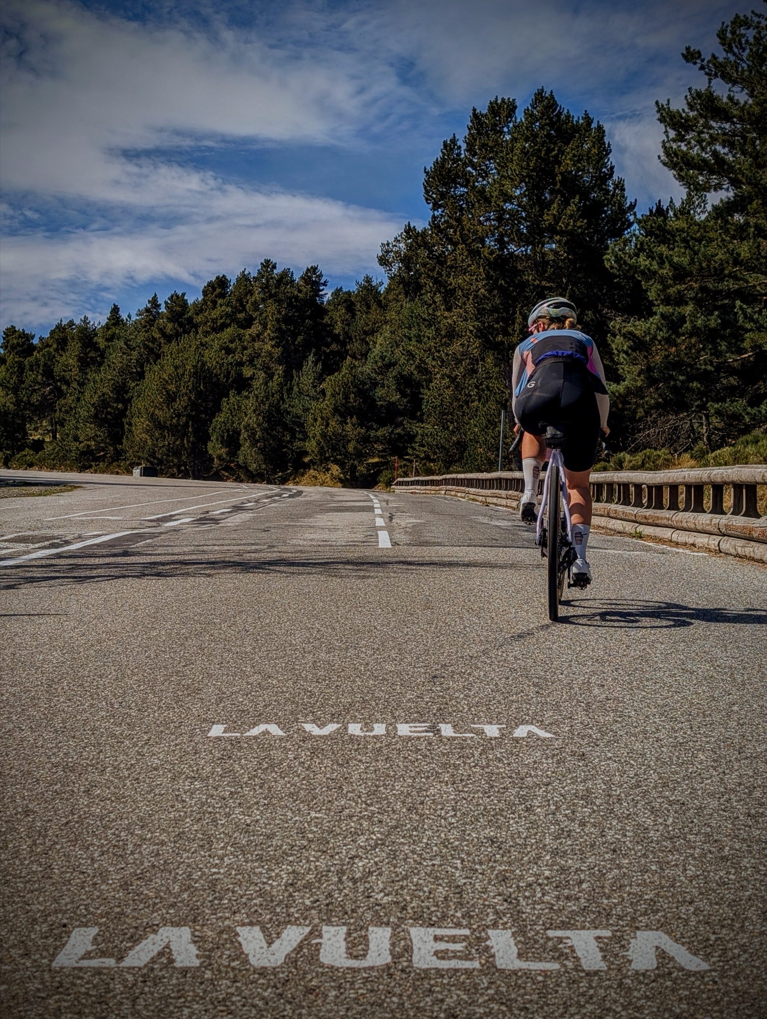 Fietser rijdt over een weg waarop in grote witte letters La Vuelta is geschilderd